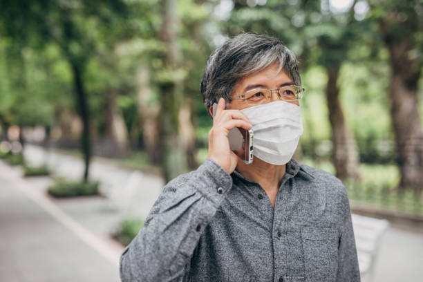 istock Man with surgical mask talking on mobile on the street 1199213440