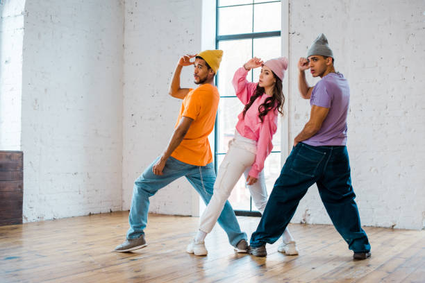 multicultural dancers touching hats while breakdancing in dance studio - modern dancing imagens e fotografias de stock