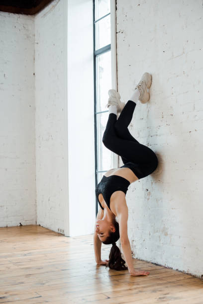 istock young woman doing handstand near brick wall in dance studio 1199213478