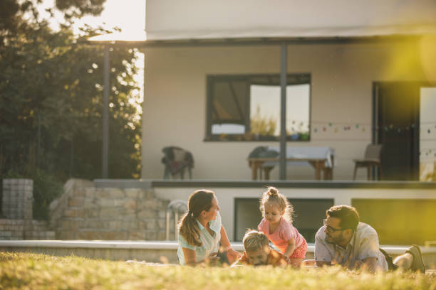 Low angle view of family of four members posing on the grass for a funny picture in front of their first house.