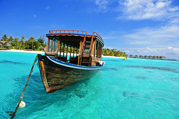 Wooden Dhoni boat on the clearwater ocean in Maldives  Maldivian dhoni in front of the turquoise bay and island maldivian culture stock pictures, royalty-free photos & images