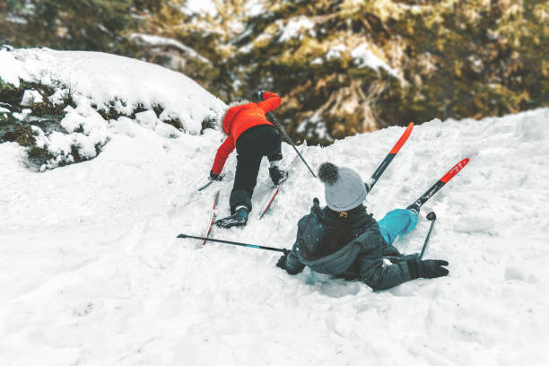 two kids on ski trying to going up hill two kids on ski trying to going up slippery hill falling behind stock pictures, royalty-free photos & images