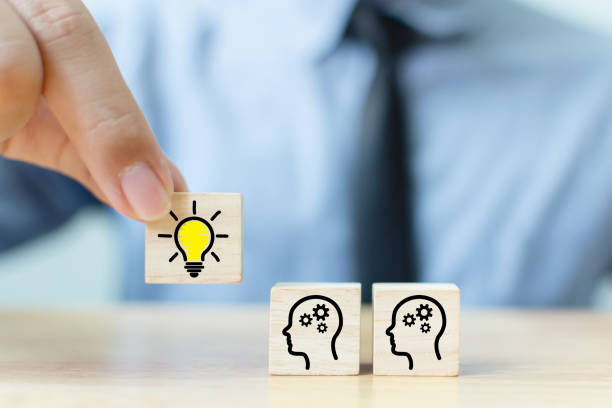 istock Concept creative idea and innovation. Hand picked wooden cube block with head human symbol and light bulb icon 1199224182