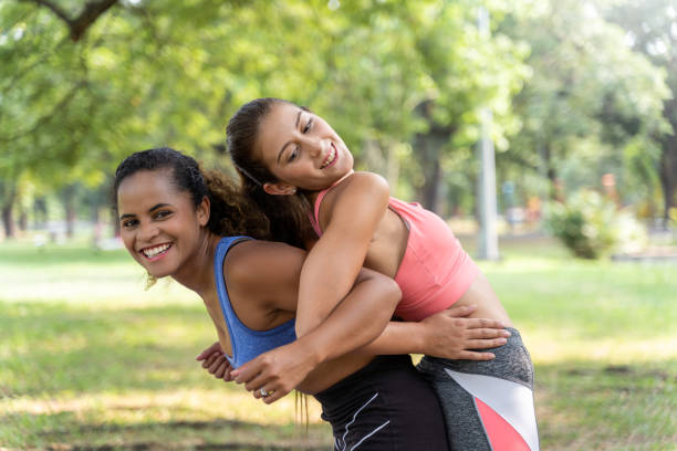 二人の女性は、公園で健康のために笑顔で運動し、定期的にジョギングをしたり、リラックスして幸せな音楽を聴いたりする友人でした。 - jogging group of people park running ストックフォトと画像