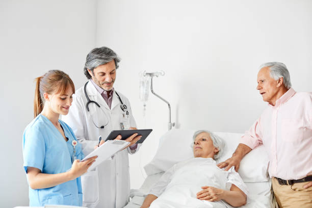 istock Healthcare workers with elderly couple in ward 1199229754