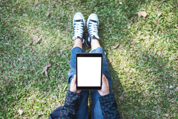 istock a woman holding and using black tablet pc with blank white desktop screen while sitting in the outdoors 1199230361