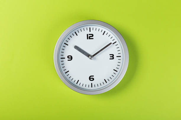istock minimalistic white wall clock with light metal on a green background. time concept. 1199231130