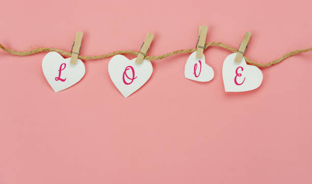 Table top view aerial image of valentine 's day background concept.Love text hang on rope clotheslines.Flat lay on modern rustic pink paper.pastel tone.Items create by handmade sign for the season. imagen aérea de la vista superior de la mesa del concepto de fondo del día de san valentín. amor texto colgar en tendederos de cuerda. el suelo plano sobre el moderno tono rústico rosa paper.pastel. artículos creados por signo hecho a mano para la tem