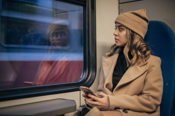 istock Young woman using smart phone in train 1199231881
