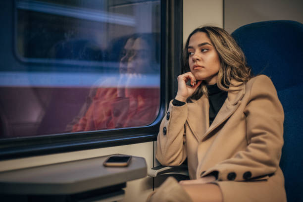 istock Young woman sitting in train and looking through the window 1199231918