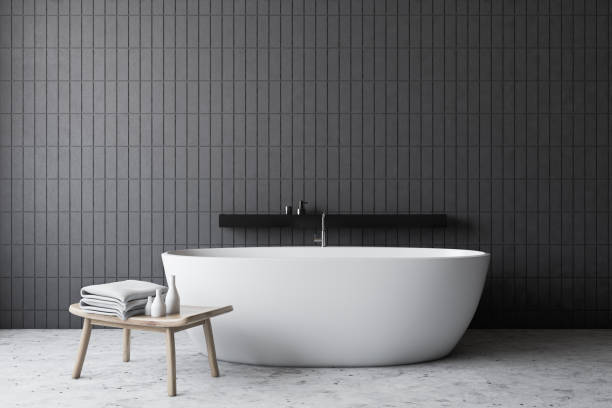 istock Gray tile bathroom with white tub and chair 1199232538