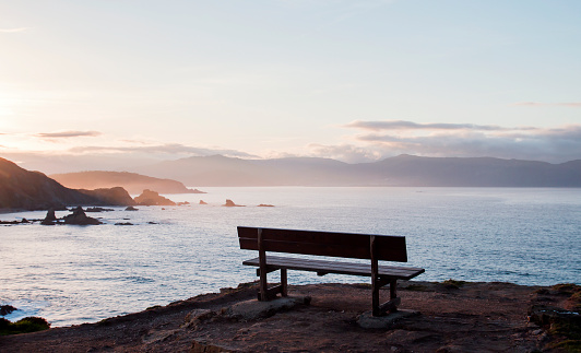 A bench with a mountain and sea view