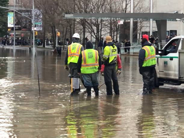 A flooded road with a Road Closed sign and barricade. The barricade is chained with a lock so drivers will not move it to drive around.