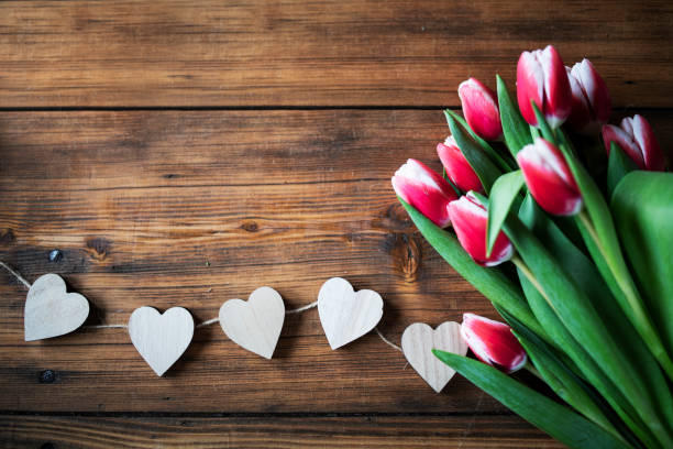 Close up of tulips flowers and hearts on wooden table, Valentine`s Day concept, Background.