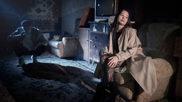 Portrait of a young woman with a gun. Carefully, she creeps up the staircase of an old building that is being modernized. It is the moment of decision. She has just raised the pistol. Dark and mysterious, in the style of film noir.