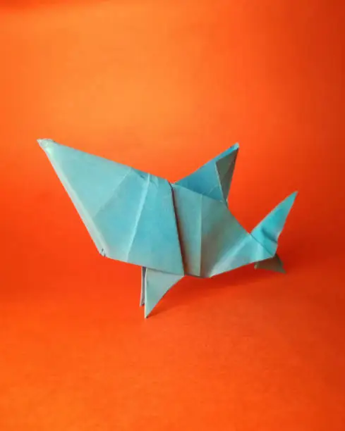 Photo of Blue shark paper origami on orange background