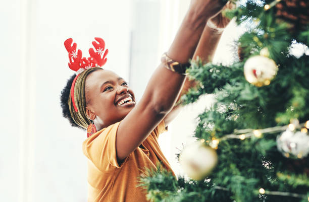 Nothing gets you in the spirit like decorating the tree Shot of an attractive young businesswoman decorating a Christmas tree in her office at work africa christmas stock pictures, royalty-free photos & images
