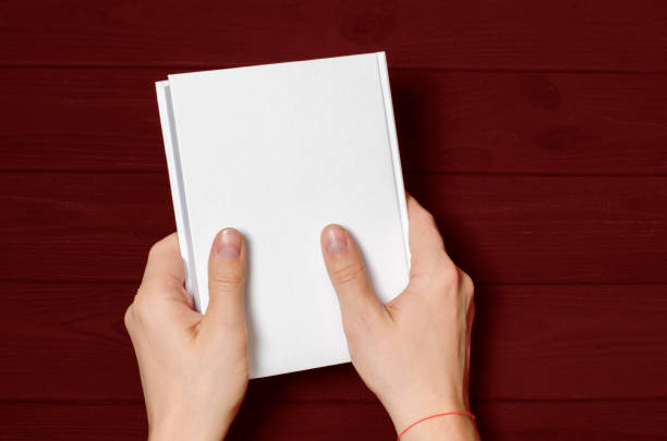 istock Men's hands holding closed book with blank cover on light background 1199239658