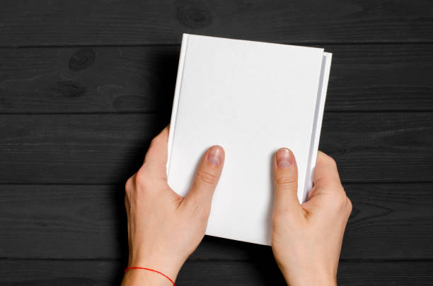 istock Men's hands holding closed book with blank cover on light background 1199239659
