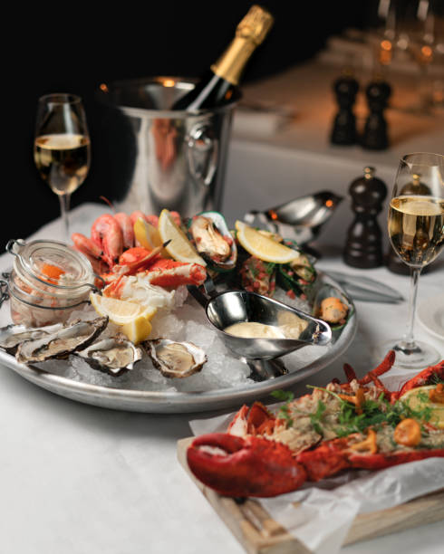 Seafood and a bottle of champagne Seafood tray, lobster, oysters, aioli, blue mussels and and champagne on a white tablecloth lobster seafood photos stock pictures, royalty-free photos & images