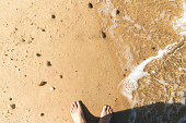 Feet on beach and a sea wave Wet sand. Sunny beach day. Vacation