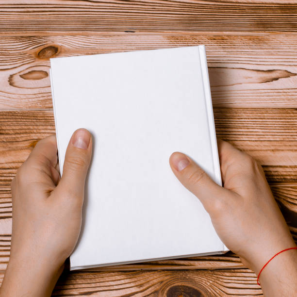 istock Men's hands holding closed book with blank cover on light background 1199244353