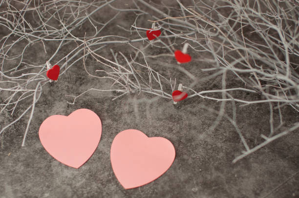 istock Holiday background for Valentine's Day on a gray cement background with white painted branches and a sheet of paper for text and red hearts. 1199246590