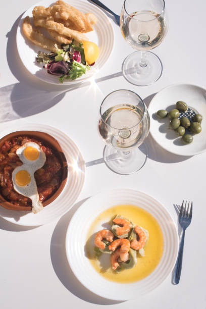 istock Spanish tapas. Shrimp with artichokes, fried squid and vegetable stew with quail eggs and olives on a white plate 1199248082