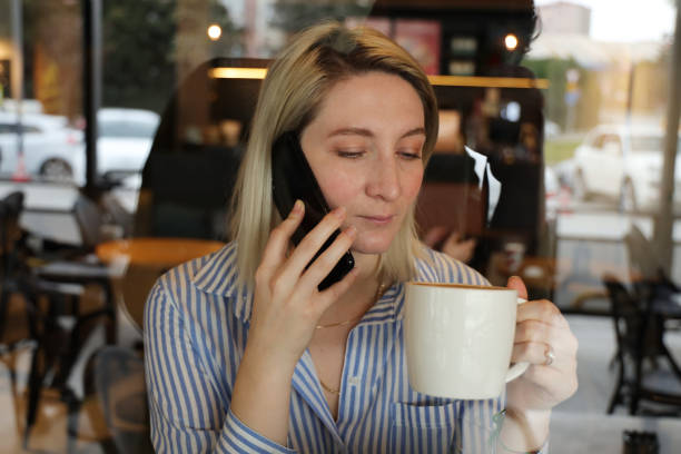 istock Businesswoman using smart phone and drinking coffee in cafe 1199248575