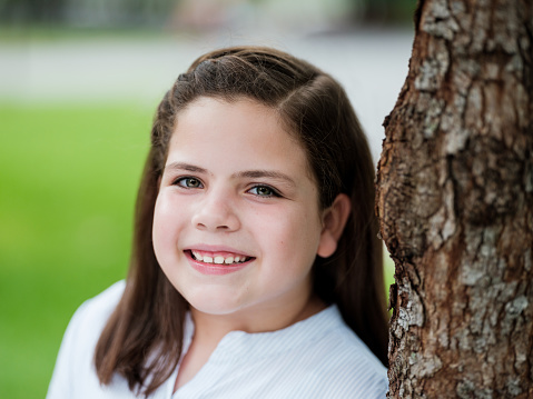 Smiling kid girl in summer park, face closeup. Child 6 years old