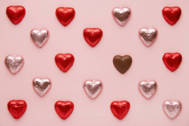 Heart shapes pattern on a pink background viewed from above. Top view of a chocolate candy hearts stock photo