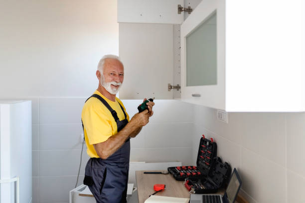 istock Elderly Handyman With an Electric Drill in His Hands Assembles the Kitchen Looking at Camera 1199254484