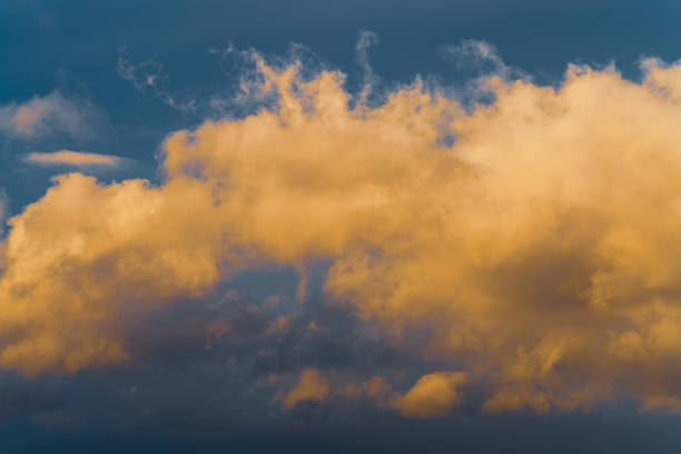 istock Beautiful golden fluffy clouds illuminated by disappearing rays at sunset floating across blue sky to change weather. Abstract meteorology background. 1199255779