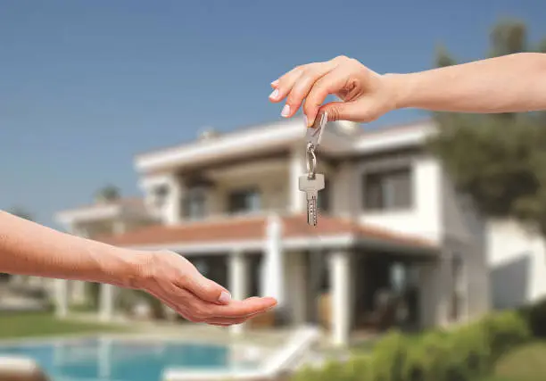 Female real estate agent giving keys from during meeting after signing rental lease contract.