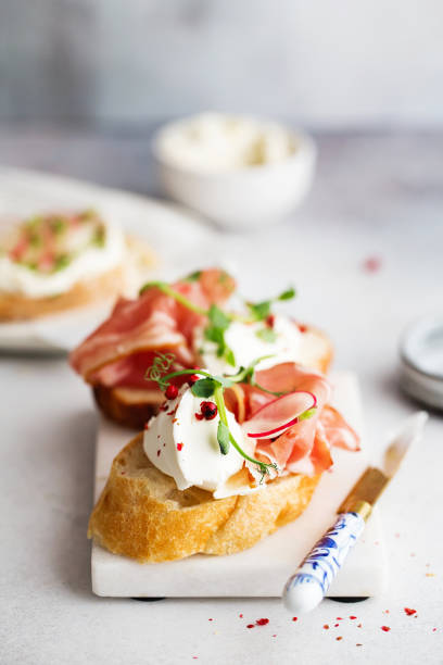 bruschetta with prosciutto and cream cheese. bread with smoked bacon and cream cheese. toasted bread slice with smoked meat and cream cheese - italian appetizer imagens e fotografias de stock