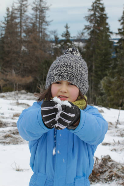 istock smiling child enjoying winter vacation playing with snow over trees 1199270658