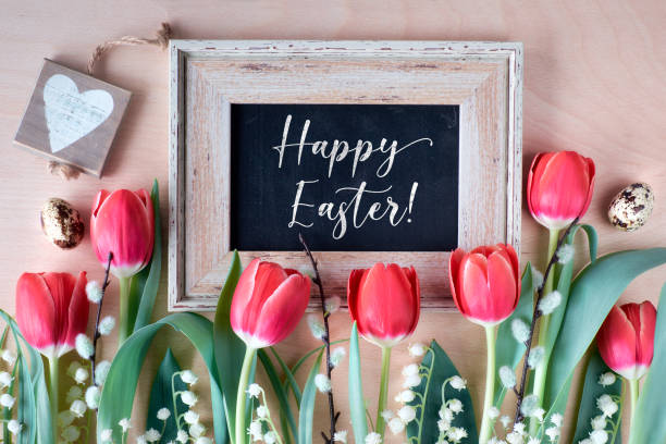 istock Happy Easter, text on blackboard on light wood with decorative ribbon and heart tag, quail eggs and spring flowers - red tulips, white lily of the valley and pussy willow. 1199270739