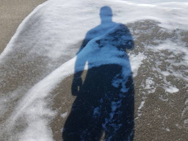 istock shadow of man on wet sand with water 1199274137