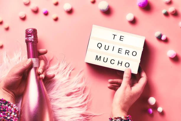 istock Valentine flat lay, top view on pink background. Hands holding lightbox with text and pink bottle of champagne on abstract pink background. Text 