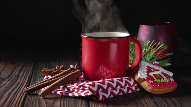 Hot chocolate in red mug with cinnamon and gingerbread on wooden background