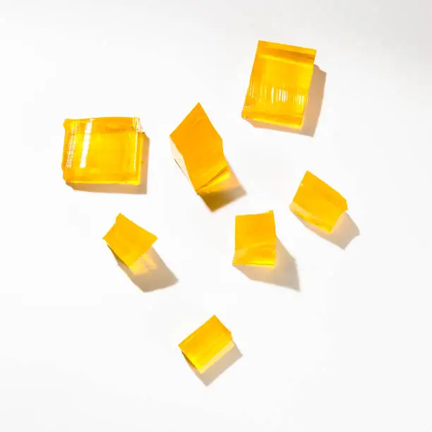 Misshapen pieces of yellow jelly, isolated on a white background