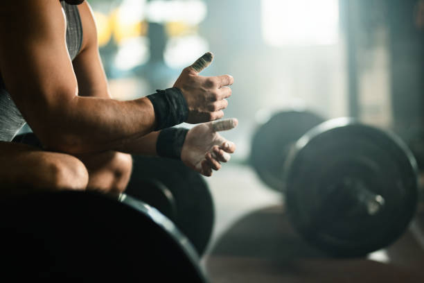 Unrecognizable bodybuilder preparing for deadlift in a gym. Unrecognizable sportsman preparing for weightlifting during cross training in a gym. crossfit chalk weightlifting weight training stock pictures, royalty-free photos & images