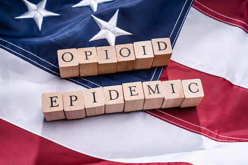 Elevated View Of Opioid Epidemic Text On Wooden Cork Over American Flag