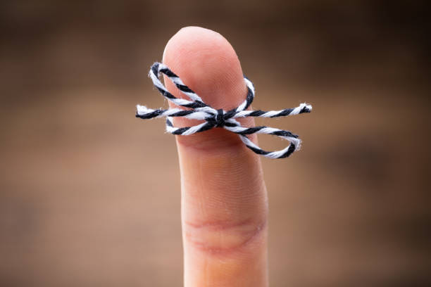 string on person's finger - reminder memories human finger string imagens e fotografias de stock