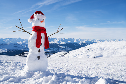 Low Angle View Of An Incomplete Snowman With Hat And Scarf On Snowy Field