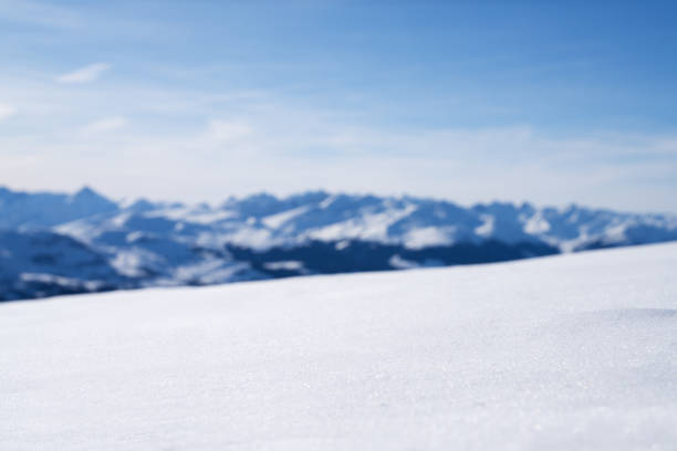 Close-up Of Snowy Landscape With Blurred Snowcapped Mountains At Background