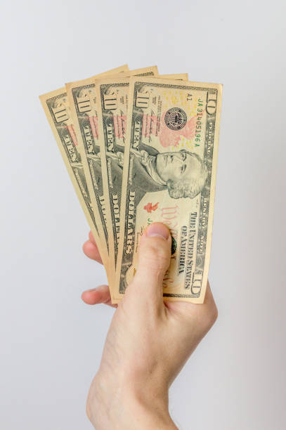 istock 10 dollar bills held in hand. 1199281587