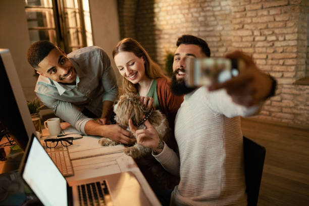 istock Happy start-up team having fun while taking selfie with their dog. 1199283773