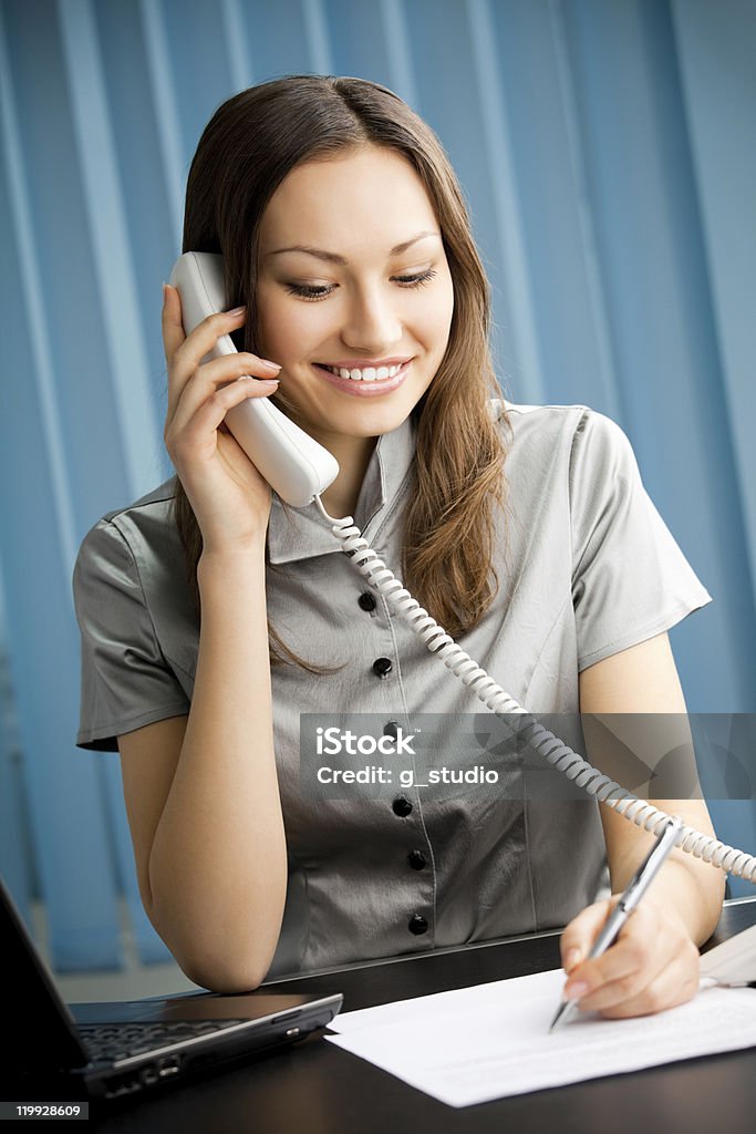 A businesswoman on a telephone while she works at office Portrait of happy smiling businesswoman with phone and document working at office Adult Stock Photo