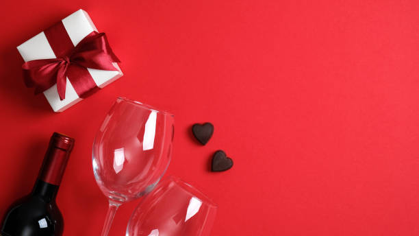 Valentine's day dinner concept. Top view table with setting for romantic dinner, bottle of wine champagne, glasses, white gift box, candies. Valentines card. Valentines day banner with copy space. concepto de cena de san valentín. mesa de vista superior con escenario para una cena romántica, botella de champán de vino, copas, caja de regalo blanca, dulces. tarjeta de san valentín. pancarta del día de san valentín con espacio de copia.